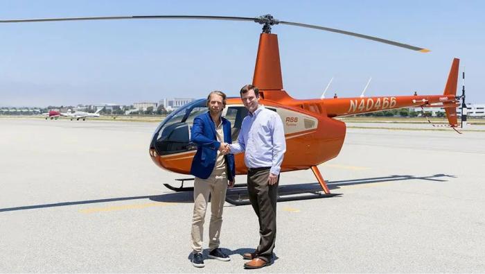 Mikaël Cardinal, vice president of program management and organ delivery systems at United Therapeutics, and David Smith, president and CEO of Robinson Helicopter Company, shake hands in front of a Robinson R66. 