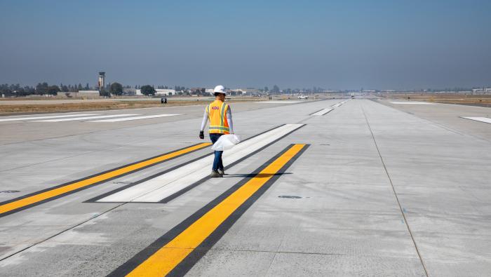 Airport worker walking KONT's newly rehabiliated Runway 8R/26L