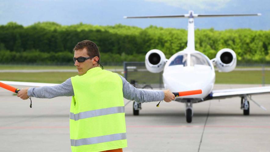 Ground crew member marshaling business jet on airport ramp