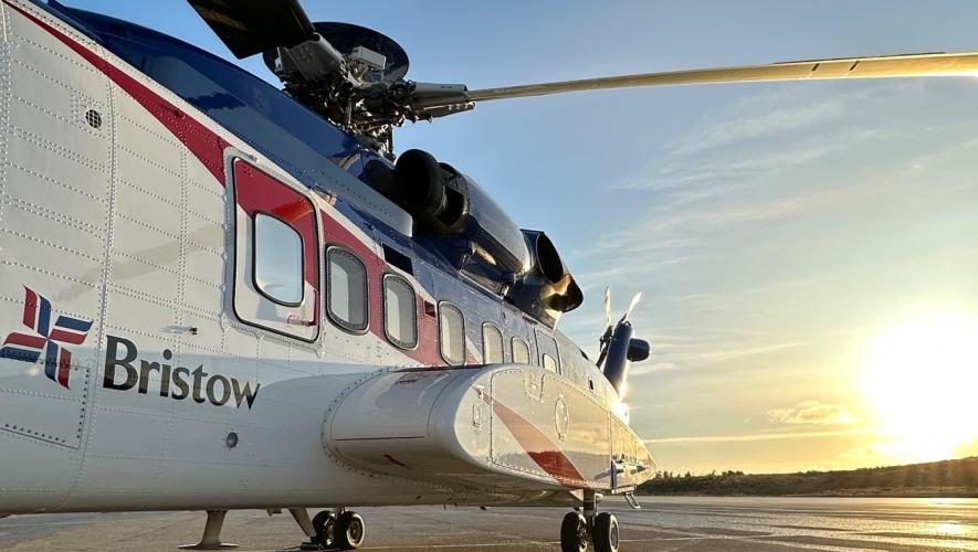 Bristow helicopter parked on airport ramp at sunset