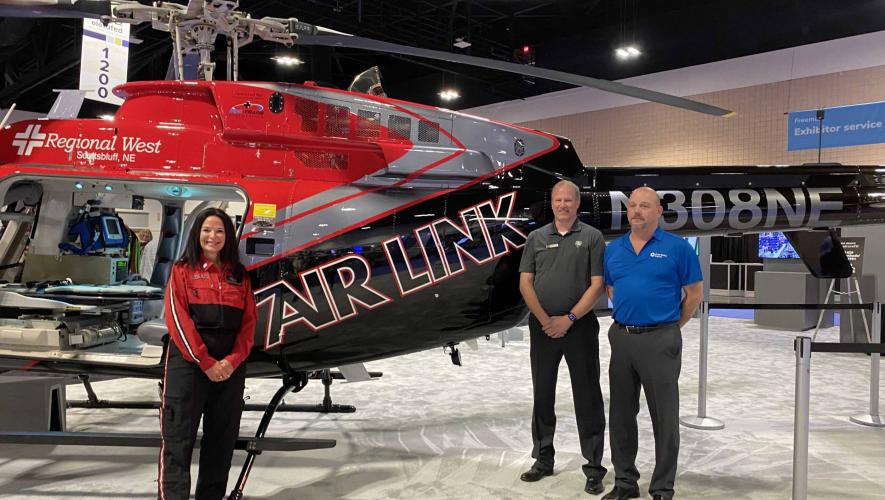 Global Medical Response employee, Bell Employee and Air Link air ambulance employee pose for photo with Bell air ambulance helicopter