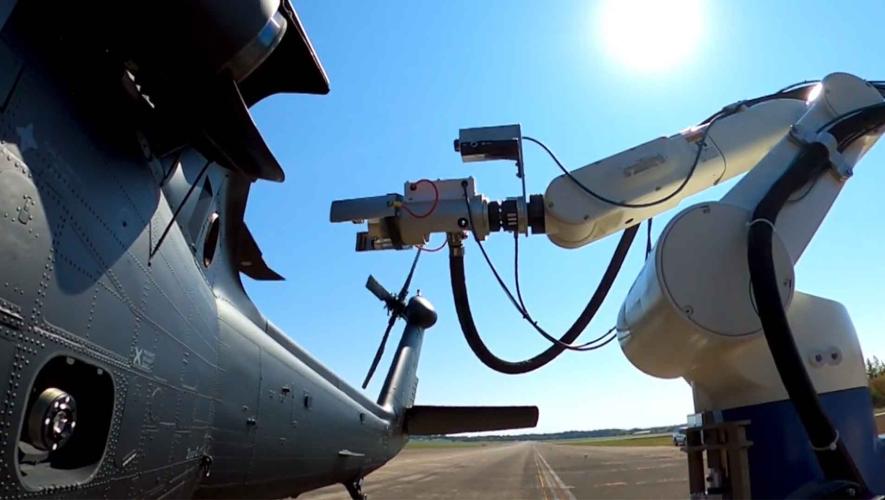 A robotic refueler is pictured next to a helicopter