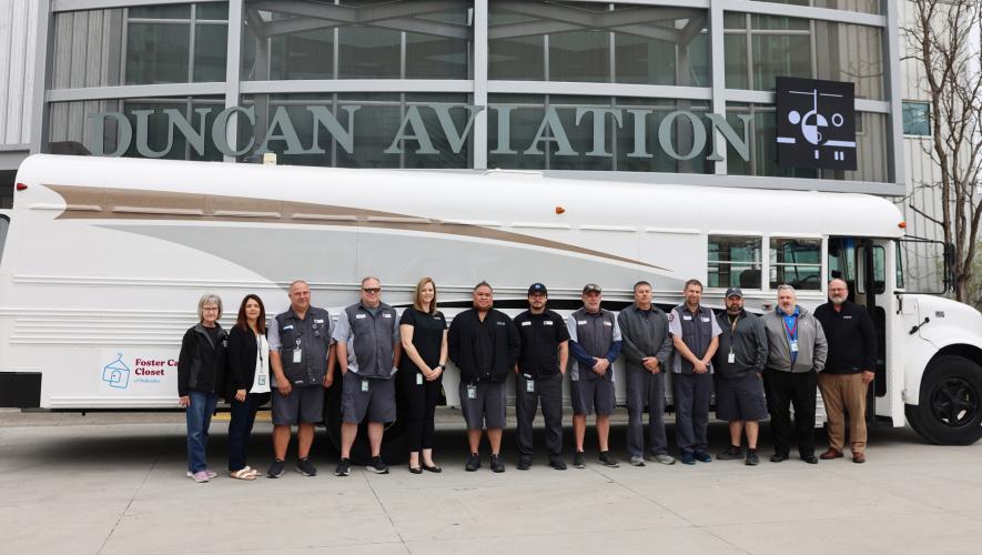 Duncan Aviation workers pose with charity bus they refurbished