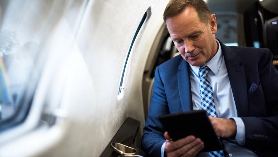 Businessman on iPad in business jet cabin