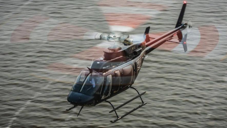Bell 407GXi helicopter in flight over ocean