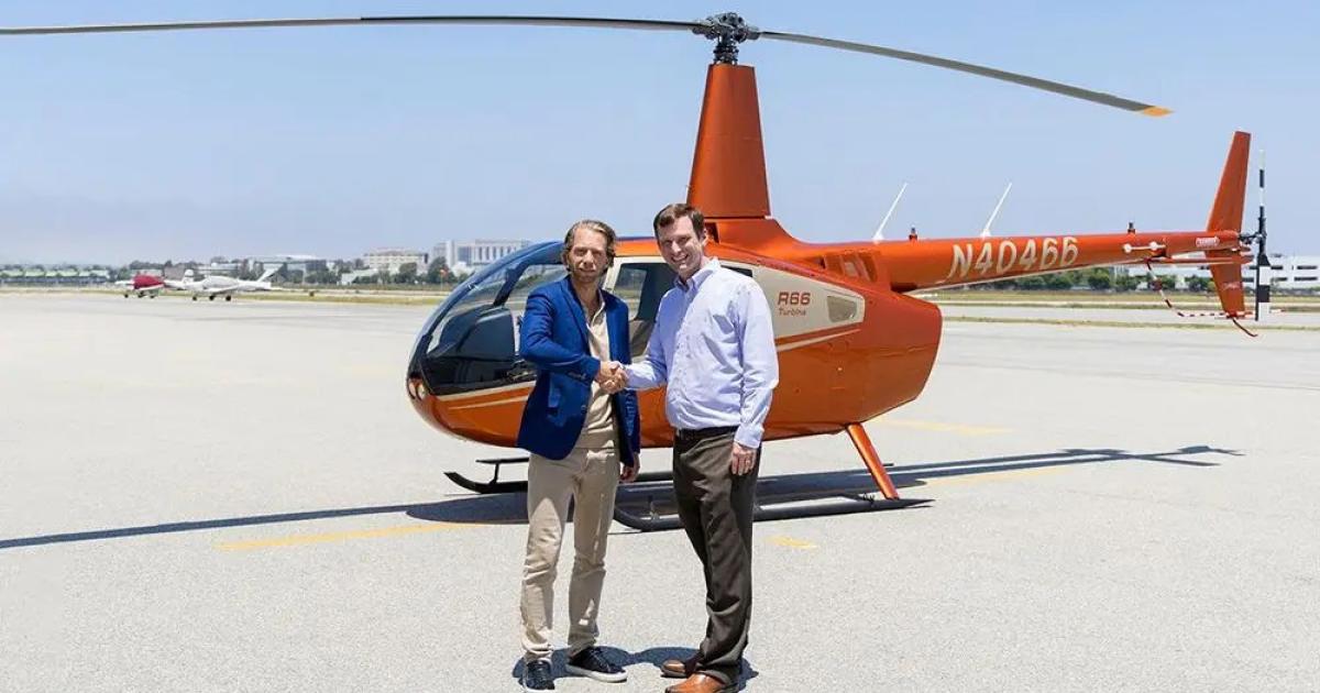 Mikaël Cardinal, vice president of program management and organ delivery systems at United Therapeutics, and David Smith, president and CEO of Robinson Helicopter Company, shake hands in front of a Robinson R66. 