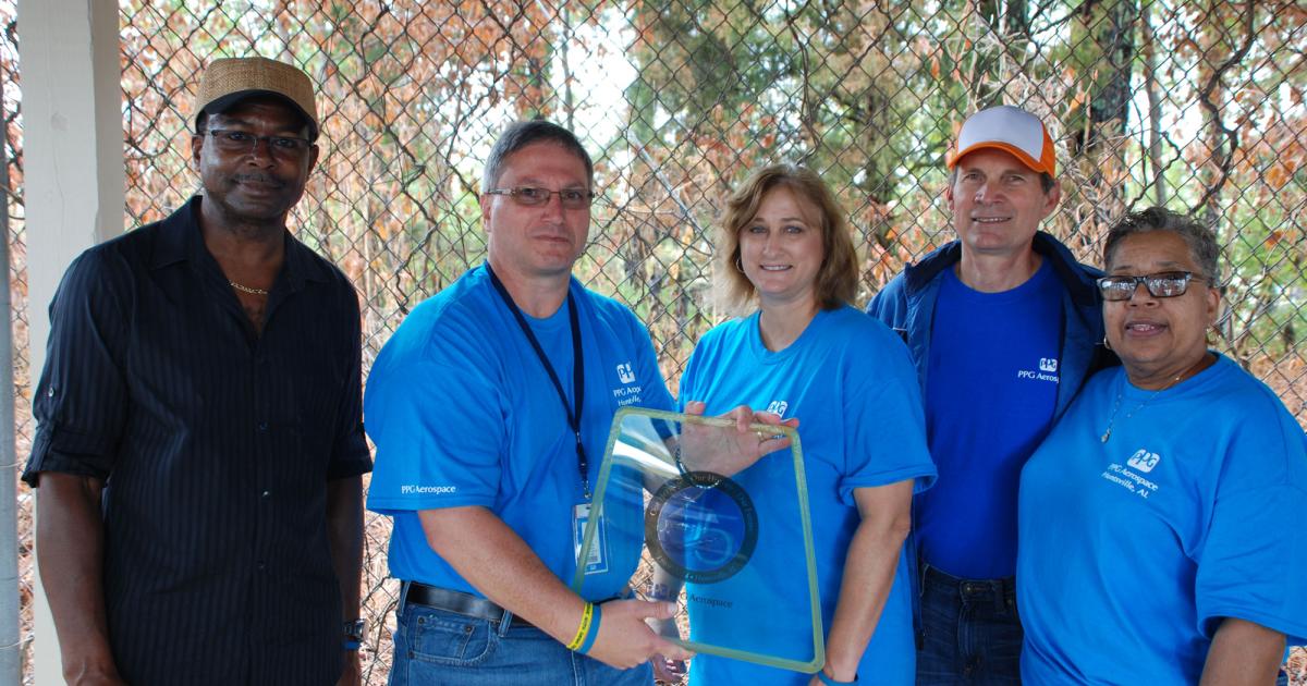 PPG Industries plant manager Tom Meyer, second from left, holds the windshield presented to him by employees at the Huntsville, Alabama, aerospace transparencies plant commemorating the facility’s 45th anniversary. Pictured with him are some production employees who have a long employment history at the plant: from left, Ray Andrews, with 41 years; Patti Tidwell, with 18 years; James Cashion, with 42 years; and Vivian Lyle, with 29 years.