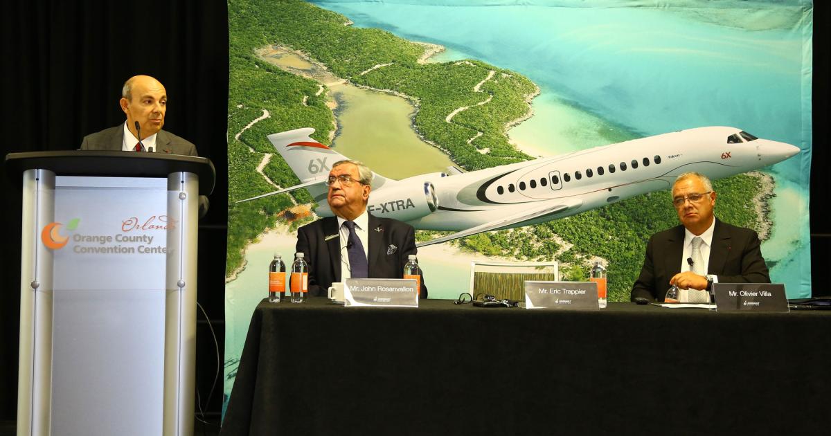 Dassault Aviation’s chairman and CEO Eric Trappier (standing) addresses reporters at his company’s press conference in advance of the 2018 edition of NBAA-BACE as Dassault Falcon Jet president and CEO John Rosanvallon (c) and sr v-p of civil aircraft Olivier Villa look on.