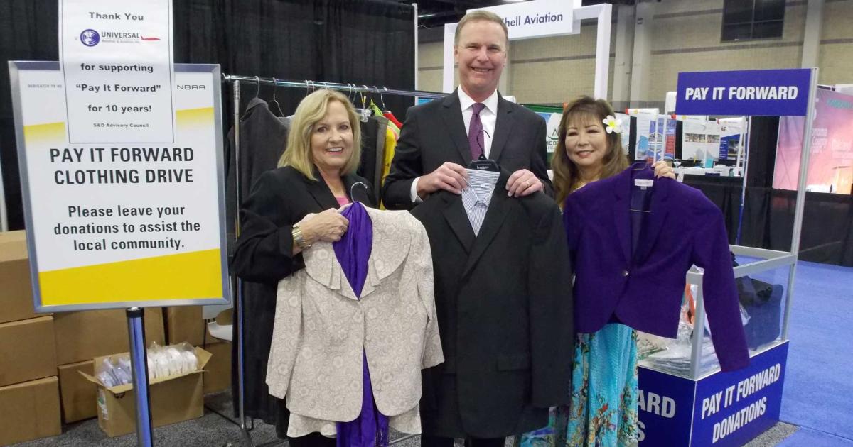 In the span of a decade, the Pay-It-Forward charity initiative has become an integral part of NBAA's annual Schedulers & Dispatchers Conference. Debbi Laux (l.), who has served as chair of the S&D advisory committee's Pay-It-Forward campaign since it began, shows off some of this year's donated clothing items along with NBAA president and CEO Ed Bolen, and Pay-It-Forward vice-chair Mi Kosasa, vice president of marketing with Air Service Hawaii. (Photo: Curt Epstein)
