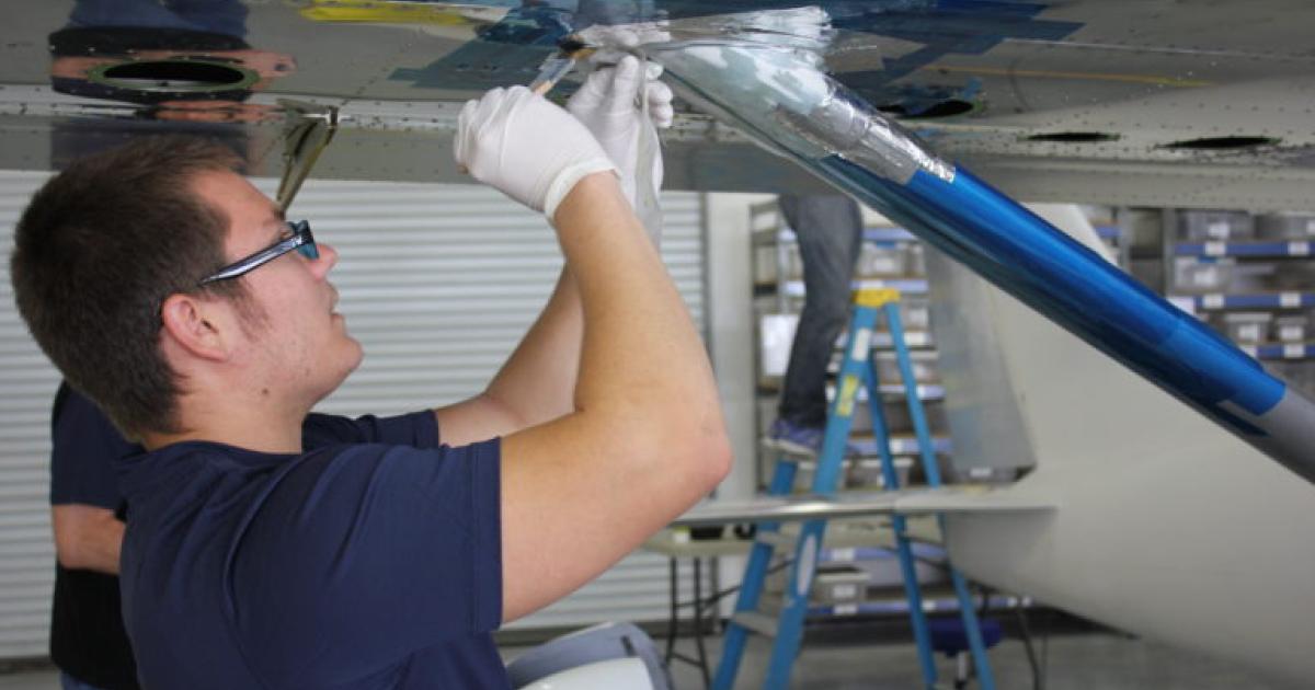 Aviation maintenance technician at work under wing of small aircraft