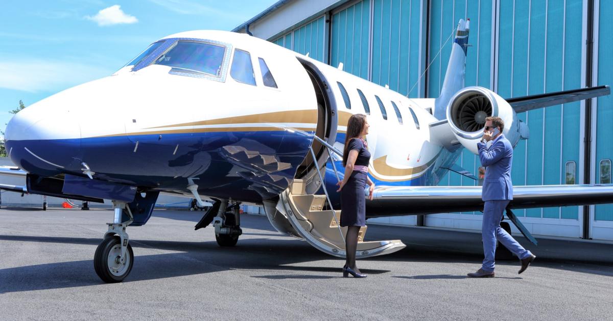 Business Jet parked in front of hangar with door open as flight crew greets business passenger